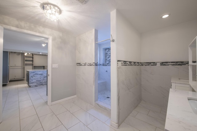 full bath with vanity, a textured ceiling, and a walk in shower