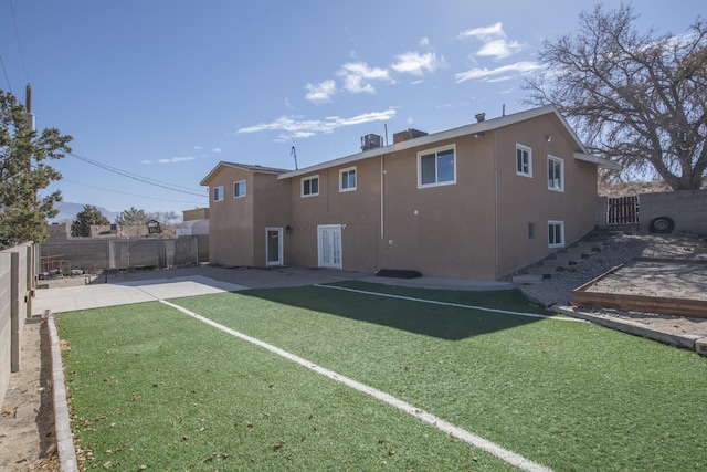 rear view of property featuring a lawn, a fenced backyard, and stucco siding