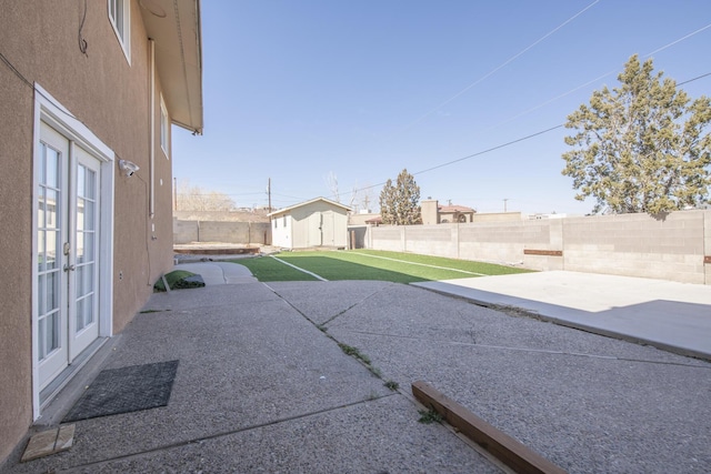 view of yard featuring a patio, a fenced backyard, an outdoor structure, french doors, and a shed