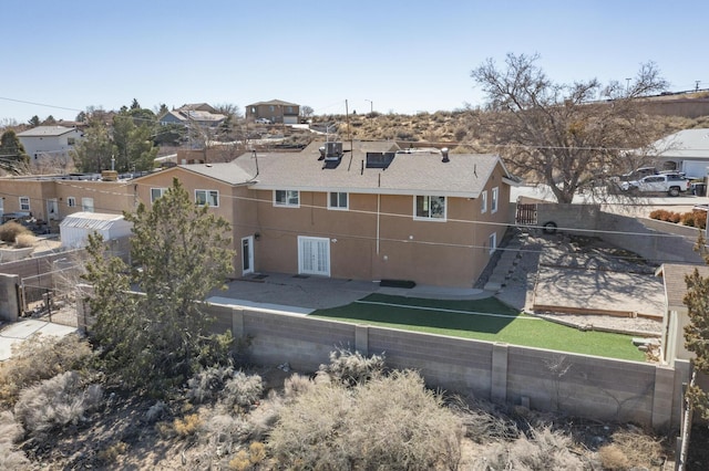 rear view of property featuring a residential view, fence, and stucco siding