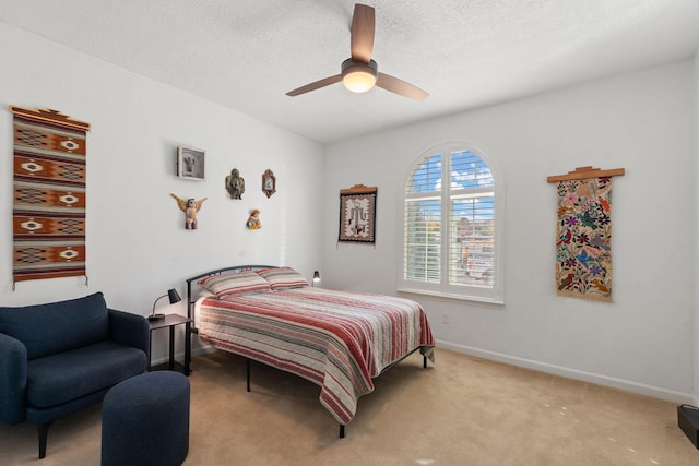 bedroom featuring light carpet, a textured ceiling, and ceiling fan