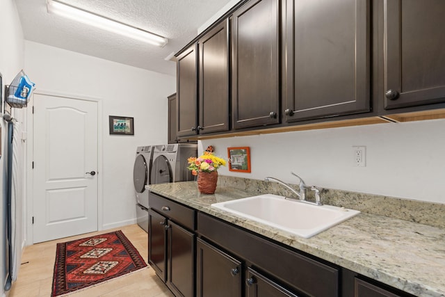 laundry area featuring washer and clothes dryer, sink, cabinets, and a textured ceiling