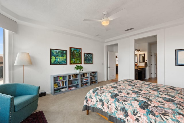 carpeted bedroom with ensuite bath, ceiling fan, and a textured ceiling