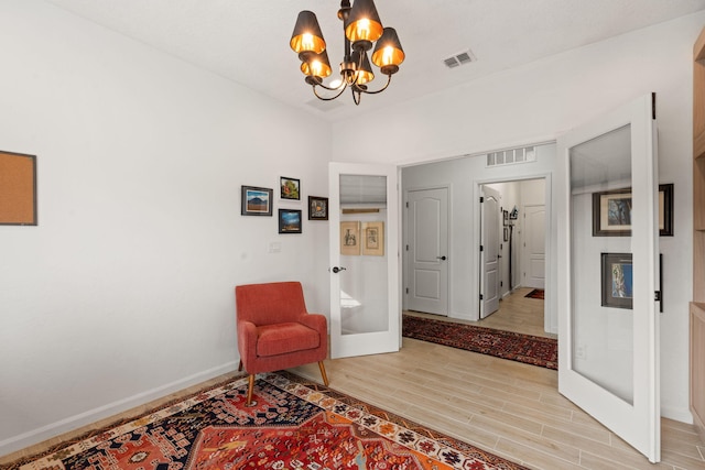 sitting room with a notable chandelier, light wood-type flooring, and french doors