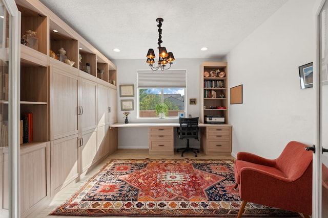 home office with built in desk, a textured ceiling, and an inviting chandelier