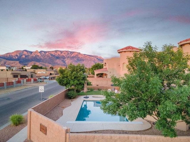 pool at dusk featuring a mountain view