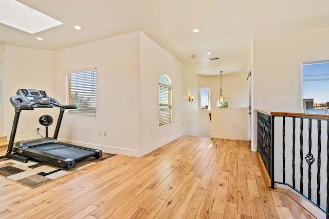 workout area with light hardwood / wood-style floors and a skylight