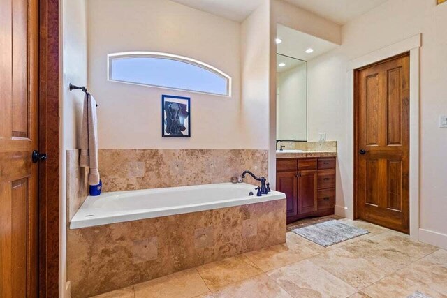 bathroom with tiled tub, tile patterned flooring, and vanity