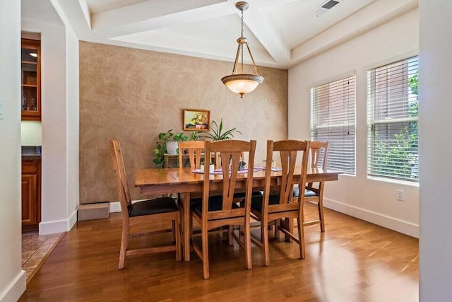 dining room with dark wood-type flooring, beamed ceiling, and a healthy amount of sunlight