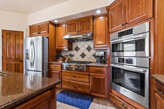 kitchen with tasteful backsplash, light tile patterned floors, dark stone counters, and appliances with stainless steel finishes