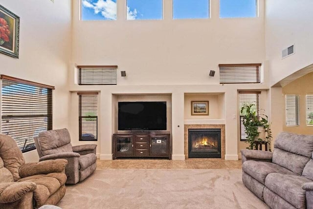 carpeted living room featuring a towering ceiling and a tile fireplace