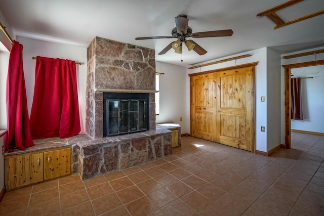 unfurnished living room with ceiling fan, a fireplace, and tile patterned flooring