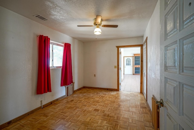 unfurnished room with ceiling fan, a textured ceiling, and light parquet floors