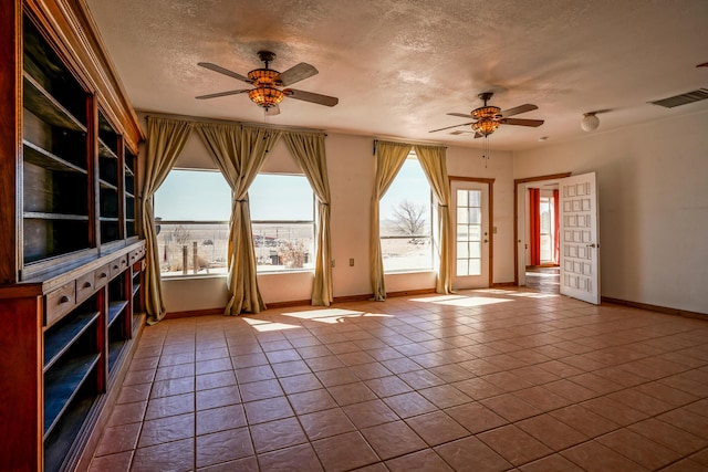 interior space with ceiling fan, light tile patterned floors, and a textured ceiling