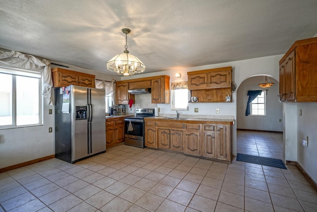 kitchen featuring hanging light fixtures, a healthy amount of sunlight, a notable chandelier, and appliances with stainless steel finishes