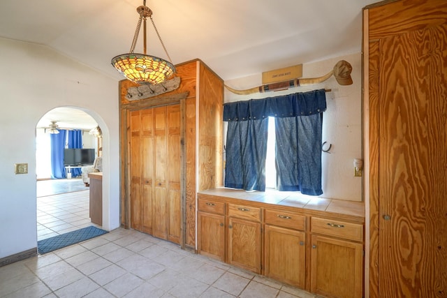 kitchen featuring pendant lighting, light tile patterned floors, vaulted ceiling, and a healthy amount of sunlight