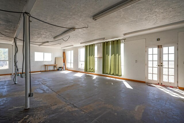 basement with a textured ceiling, a wealth of natural light, and french doors