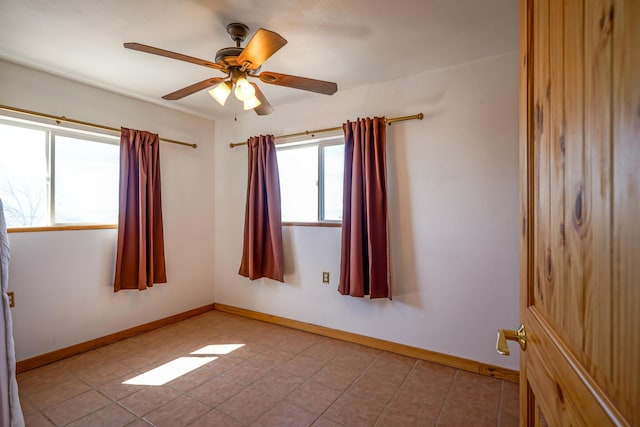 tiled empty room with a wealth of natural light and ceiling fan