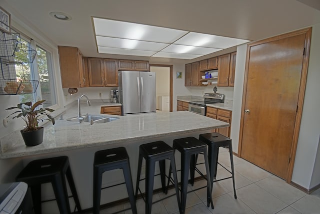 kitchen with kitchen peninsula, a kitchen breakfast bar, light stone countertops, stainless steel appliances, and sink