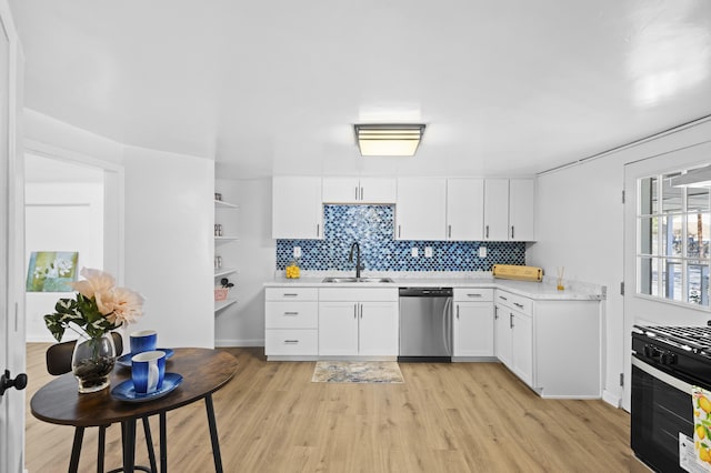 kitchen featuring stainless steel dishwasher, sink, light hardwood / wood-style flooring, white cabinetry, and range with gas stovetop