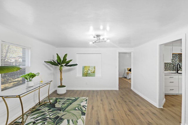 unfurnished room featuring a chandelier, light wood-type flooring, and sink