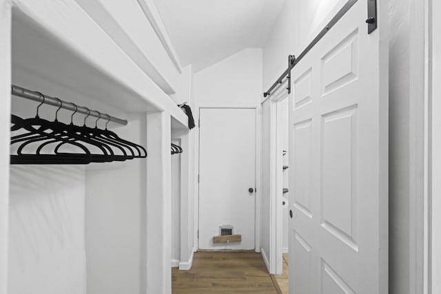 mudroom with a barn door, dark wood-type flooring, and lofted ceiling