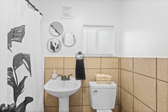 bathroom featuring sink, toilet, and tile walls