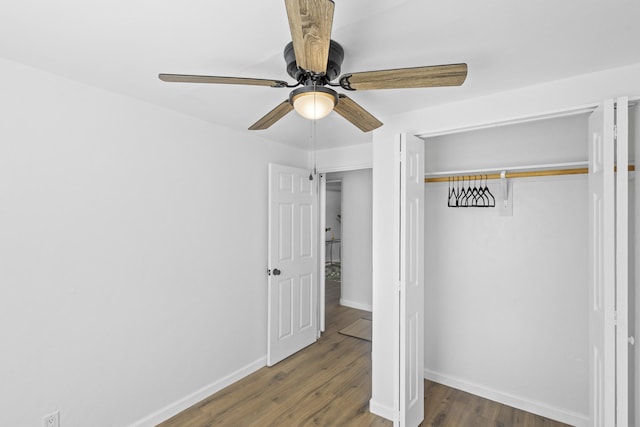 unfurnished bedroom featuring ceiling fan, a closet, and dark wood-type flooring