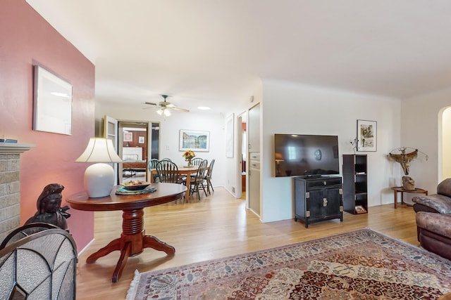 living room featuring a fireplace, light hardwood / wood-style floors, and ceiling fan