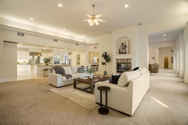 living room featuring ceiling fan, light colored carpet, and a premium fireplace