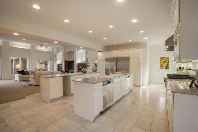 kitchen featuring light stone counters, white cabinets, a spacious island, and appliances with stainless steel finishes