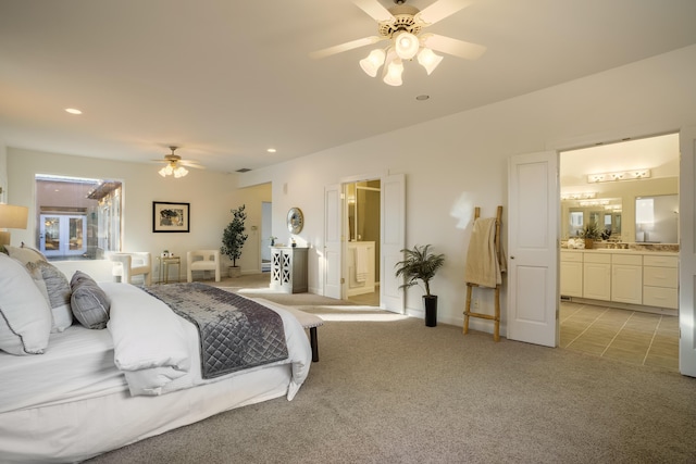 bedroom featuring ceiling fan, light colored carpet, and ensuite bath