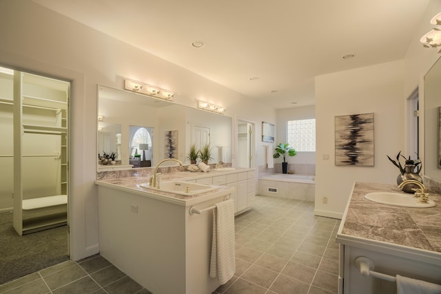 bathroom featuring tile patterned flooring, vanity, and tiled tub