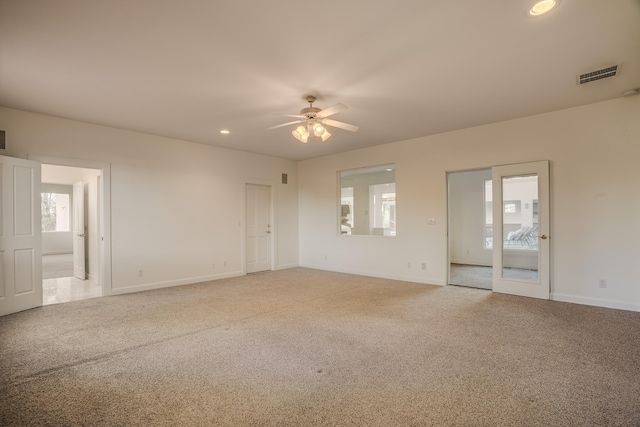 carpeted spare room featuring a healthy amount of sunlight and ceiling fan