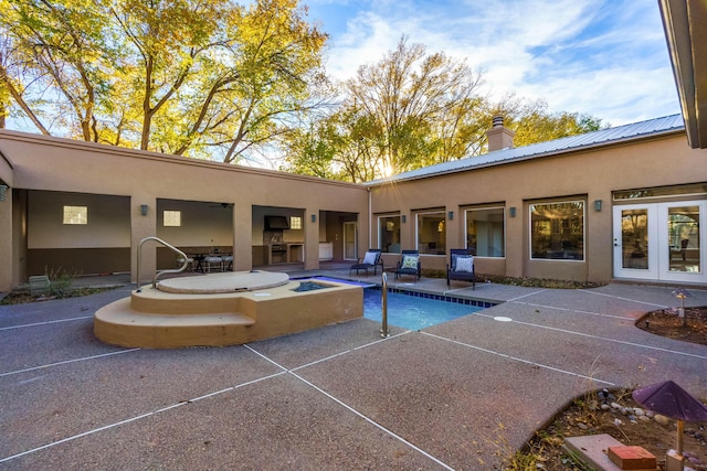 view of swimming pool featuring a jacuzzi, a patio, and french doors