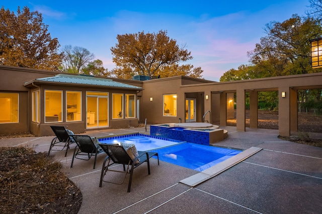 back house at dusk with a patio and a pool with hot tub