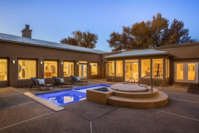 back house at dusk featuring a fire pit and a patio area