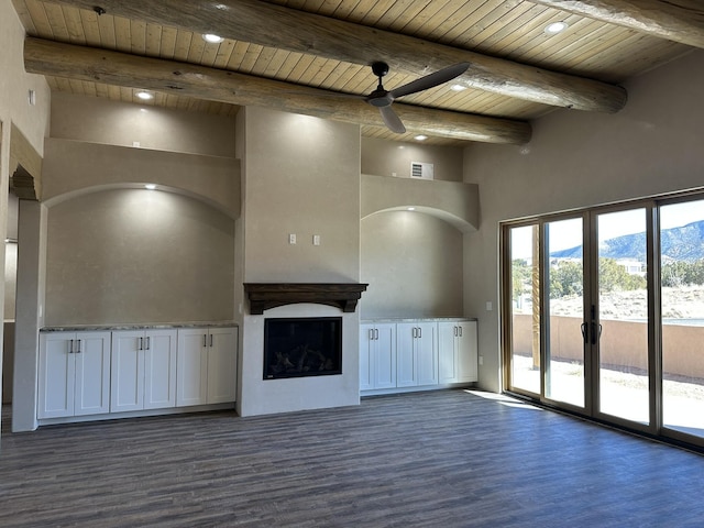 unfurnished living room with dark wood-type flooring, beamed ceiling, a mountain view, and wooden ceiling