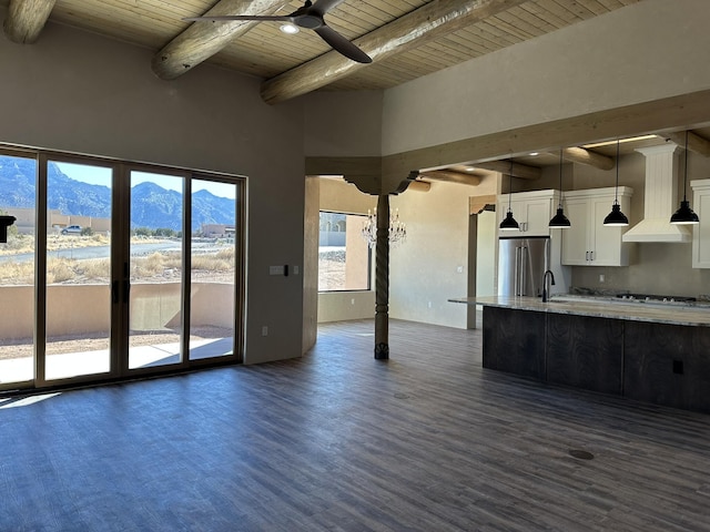 unfurnished living room with sink, wood ceiling, dark hardwood / wood-style floors, a mountain view, and ceiling fan