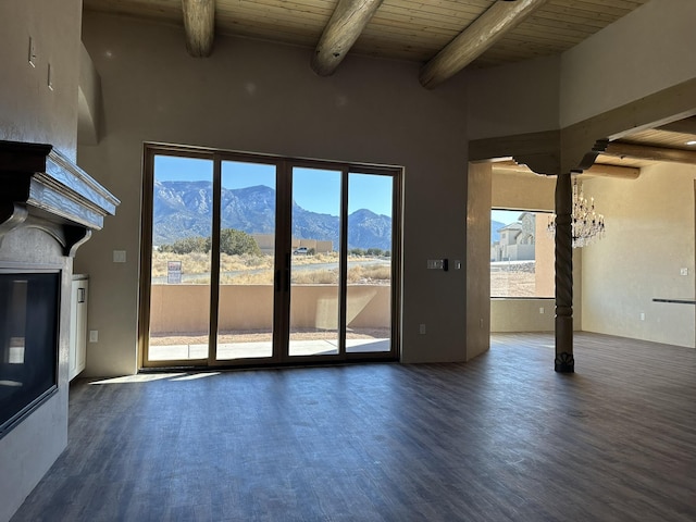 unfurnished living room with beamed ceiling, a mountain view, dark wood-type flooring, and wooden ceiling