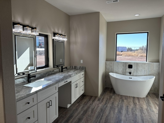 bathroom featuring hardwood / wood-style flooring, vanity, a washtub, and tile walls