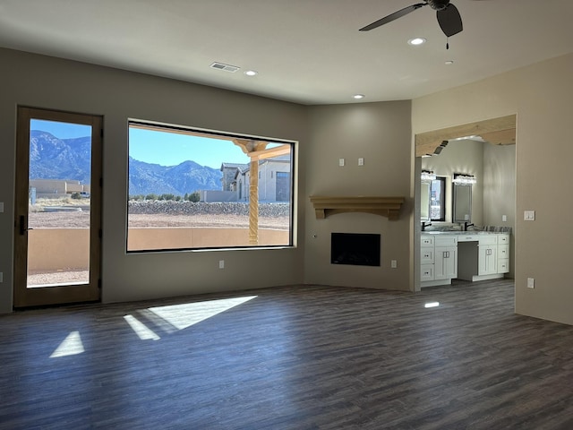 unfurnished living room with ceiling fan, a mountain view, and dark hardwood / wood-style flooring