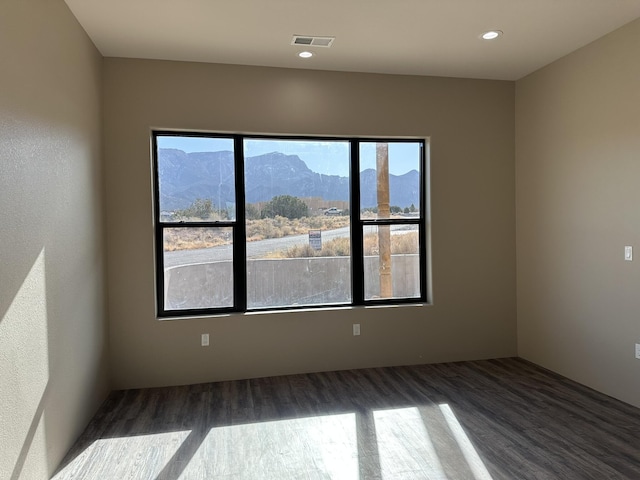 unfurnished room featuring a mountain view and dark hardwood / wood-style floors