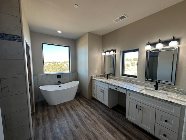 bathroom featuring a tub to relax in, tile walls, wood-type flooring, and vanity