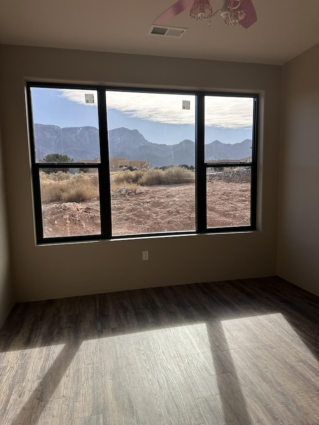 unfurnished room with hardwood / wood-style flooring and a mountain view