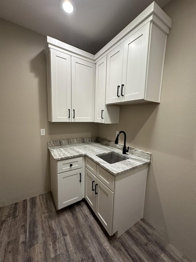 kitchen featuring sink, dark wood-type flooring, white cabinets, and light stone counters