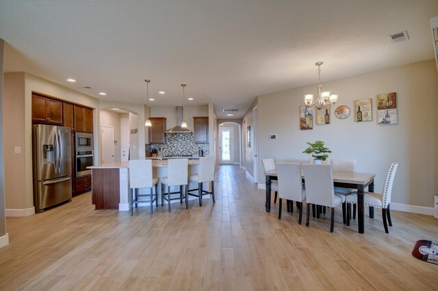 dining space with a notable chandelier and light hardwood / wood-style flooring