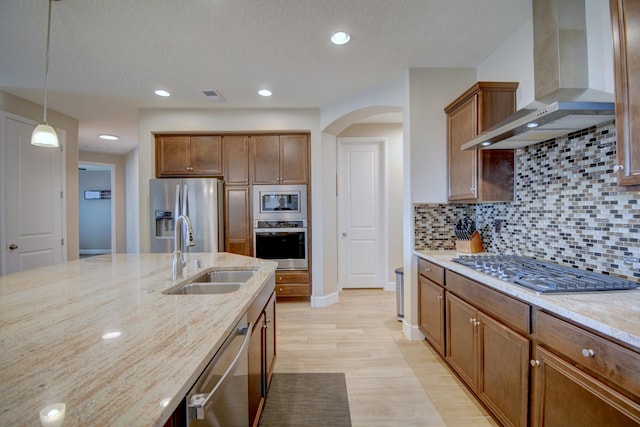 kitchen featuring arched walkways, stainless steel appliances, visible vents, a sink, and wall chimney exhaust hood