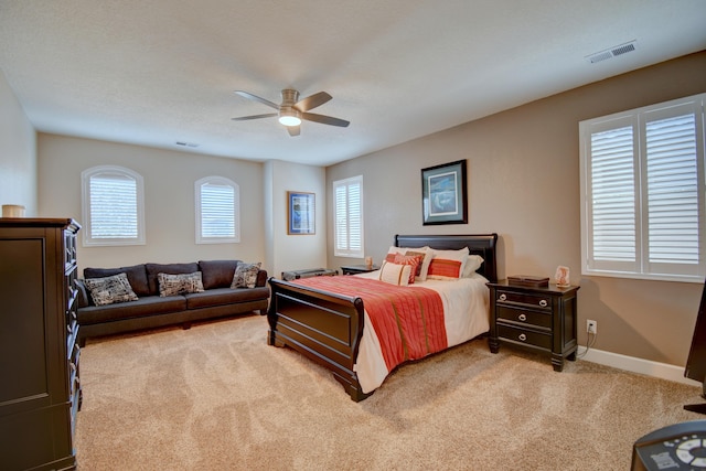 bedroom featuring baseboards, multiple windows, visible vents, and light colored carpet