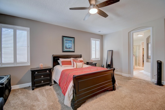 carpeted bedroom featuring ensuite bath, ceiling fan, and a textured ceiling